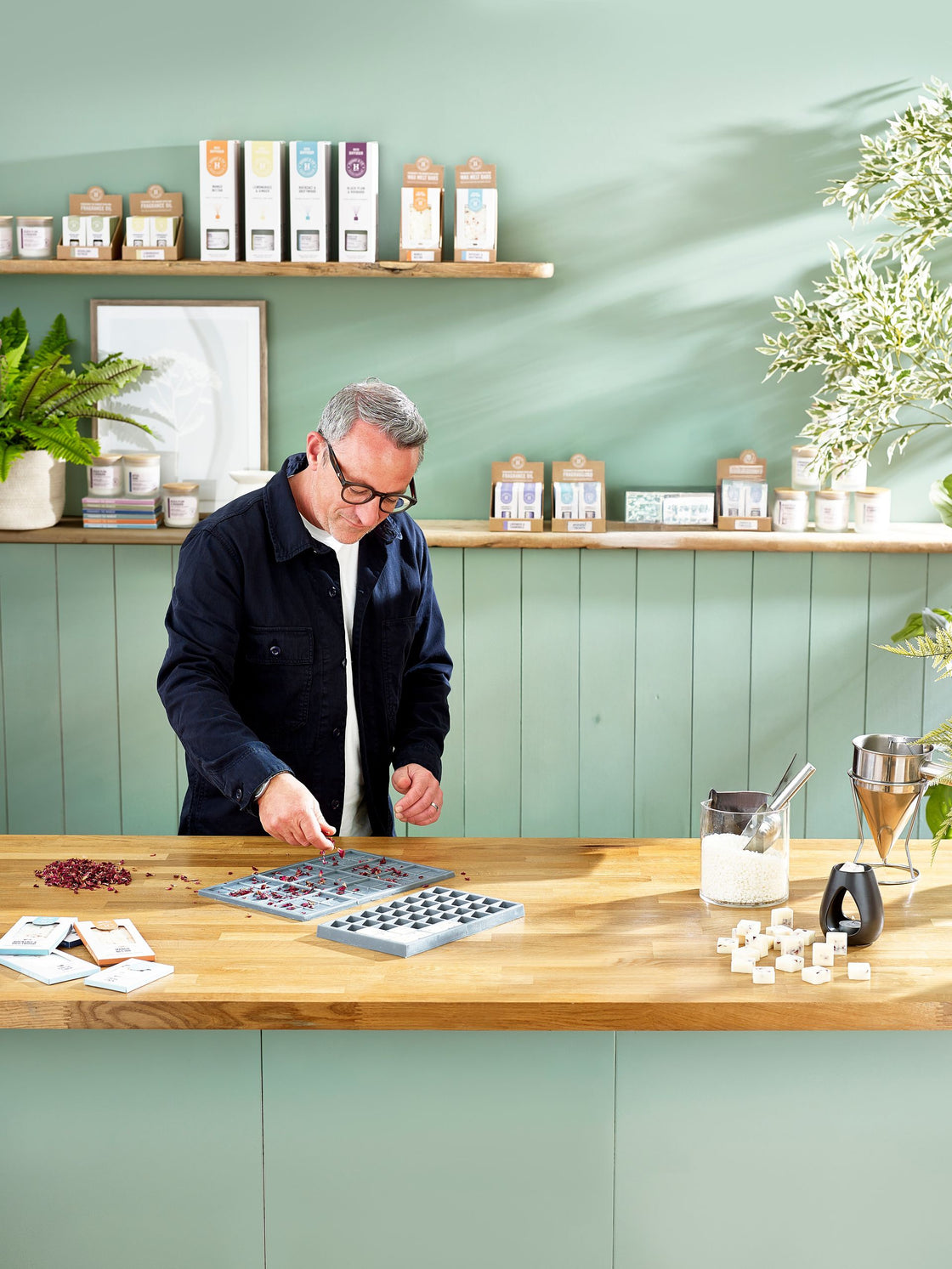 Mark, founder of Henry & Co, pressing rose petals into a wax melt mould at the workshop bench